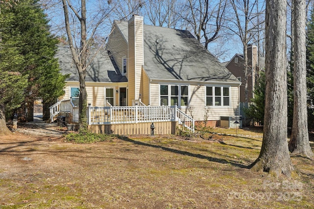 new england style home featuring a front yard, central AC, a chimney, and a wooden deck