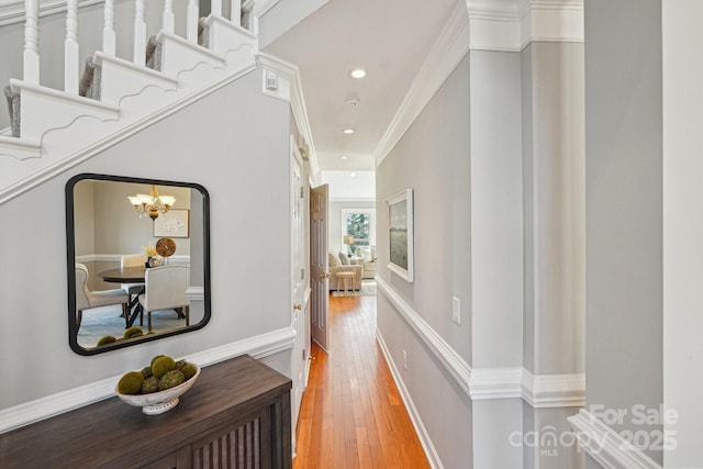 hallway with arched walkways, recessed lighting, crown molding, hardwood / wood-style floors, and an inviting chandelier