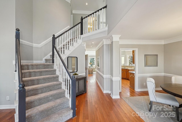 interior space with crown molding, hardwood / wood-style floors, decorative columns, and baseboards