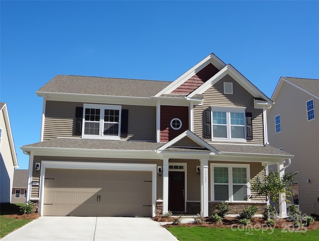 craftsman inspired home with a garage, concrete driveway, and roof with shingles