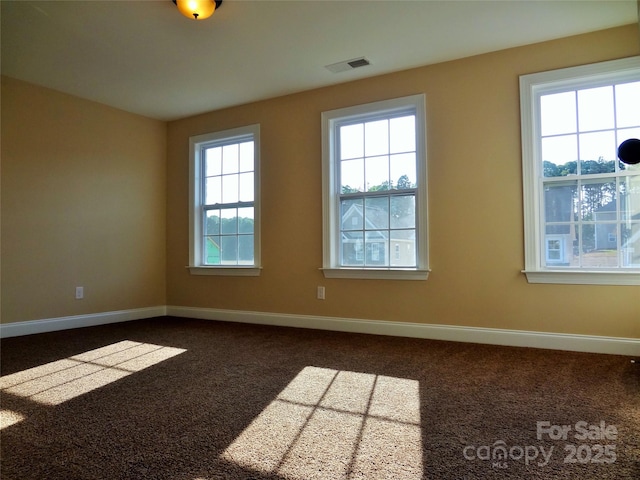 unfurnished room with carpet, visible vents, and baseboards