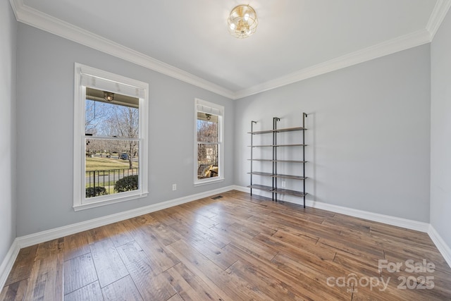 spare room featuring crown molding, visible vents, baseboards, and hardwood / wood-style floors