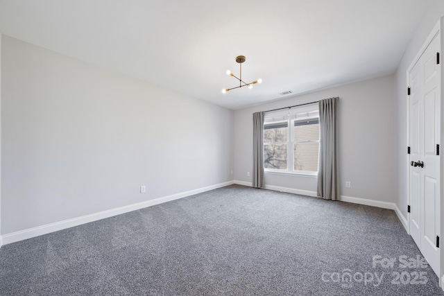 empty room with carpet flooring, a notable chandelier, visible vents, and baseboards