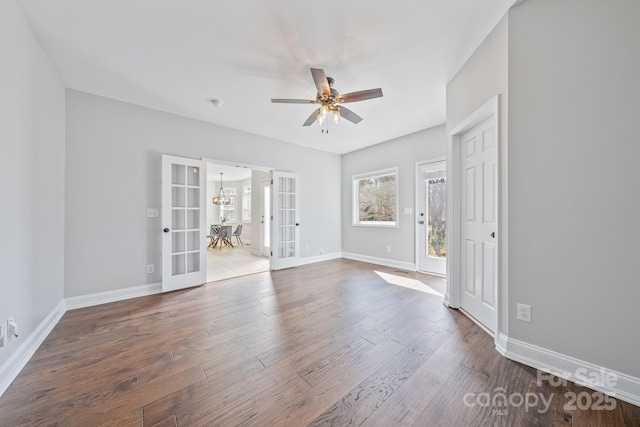 spare room with ceiling fan with notable chandelier, french doors, baseboards, and wood finished floors