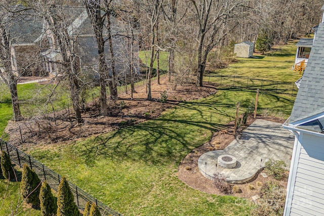 view of yard with a storage shed, an outdoor fire pit, an outbuilding, and a fenced backyard