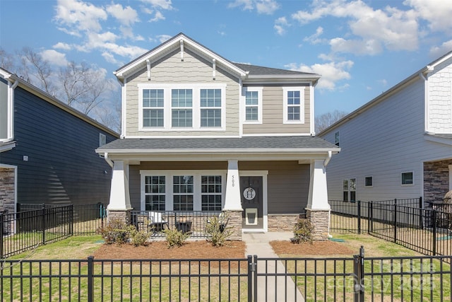 craftsman-style house with a fenced front yard, roof with shingles, covered porch, stone siding, and a front lawn