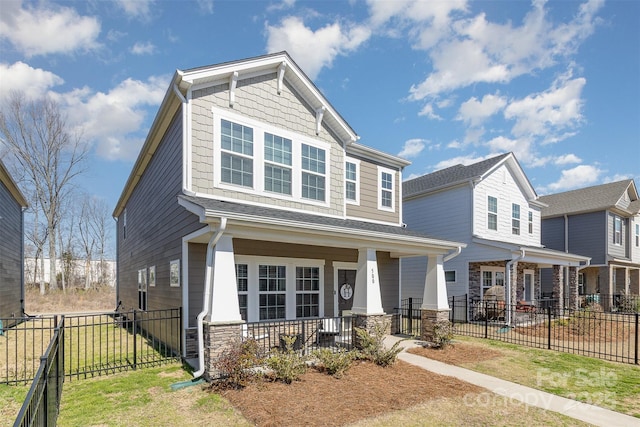 craftsman-style home with covered porch, stone siding, and fence