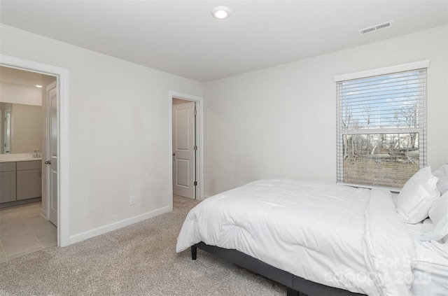 bedroom with light carpet, baseboards, visible vents, and connected bathroom