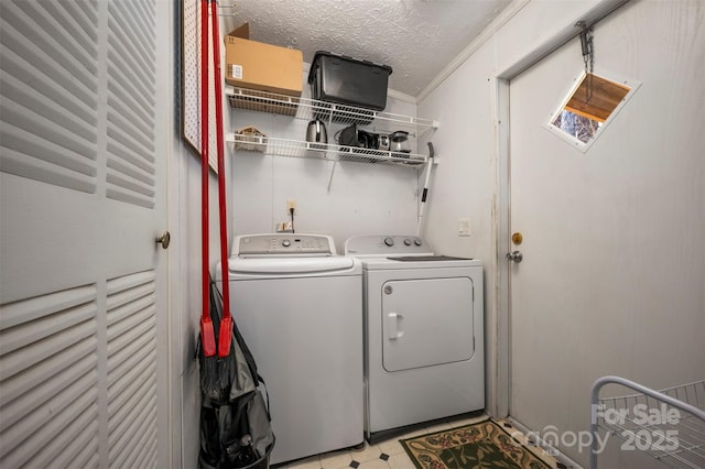 clothes washing area with washing machine and dryer, laundry area, a textured ceiling, and light floors