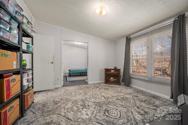 bedroom with carpet, a lit fireplace, and a textured ceiling