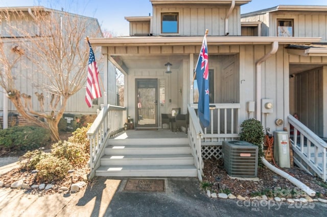 doorway to property with covered porch, central AC, and board and batten siding