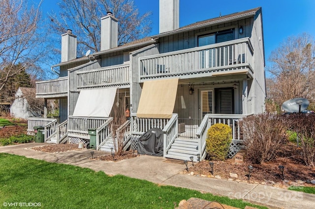 exterior space featuring a porch, a chimney, a balcony, and board and batten siding