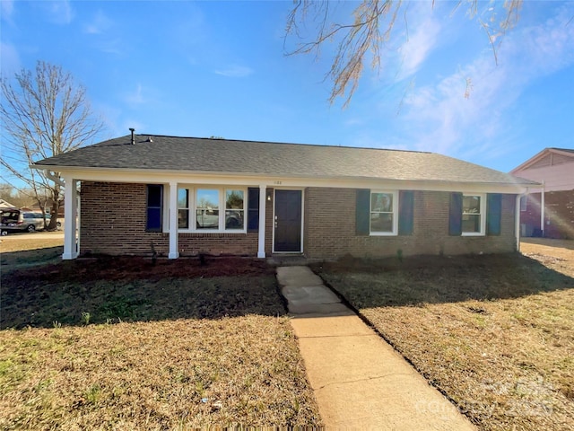 ranch-style house with brick siding, roof with shingles, and a front yard