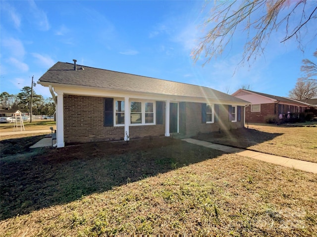 back of property with brick siding, a lawn, and roof with shingles