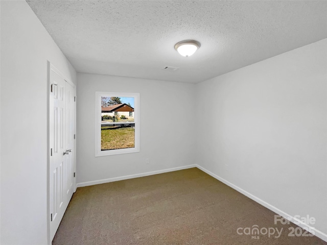 unfurnished bedroom with carpet floors, visible vents, a textured ceiling, and baseboards