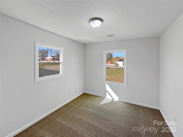 spare room featuring a healthy amount of sunlight, baseboards, visible vents, and dark colored carpet