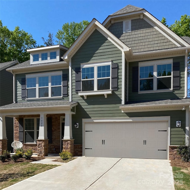 craftsman inspired home with a garage, stone siding, covered porch, and concrete driveway