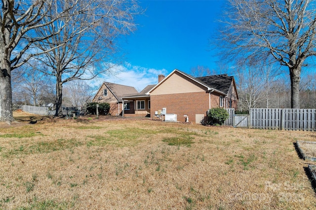 exterior space with brick siding, fence, a lawn, a gate, and a chimney