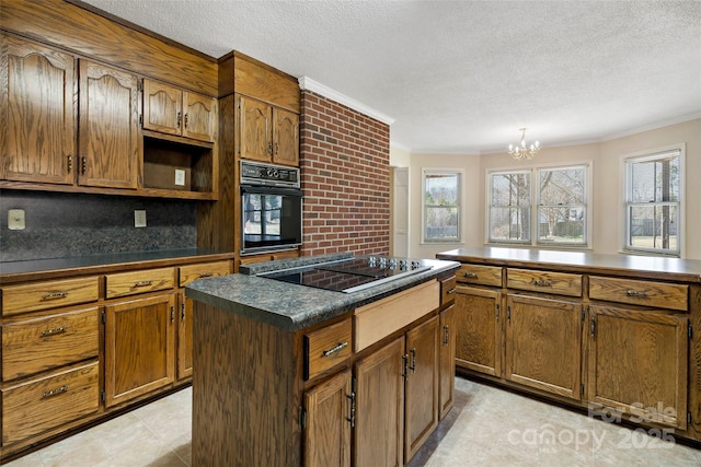 kitchen featuring crown molding, dark countertops, a kitchen island, a textured ceiling, and black appliances