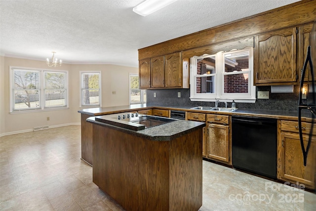 kitchen featuring brown cabinetry, dark countertops, an inviting chandelier, black appliances, and a sink