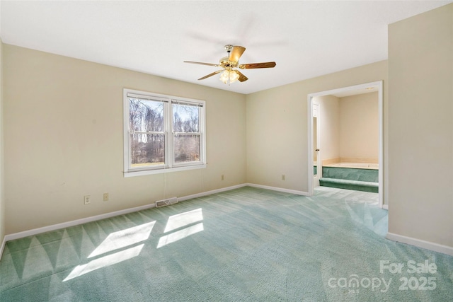 empty room with carpet flooring, ceiling fan, visible vents, and baseboards