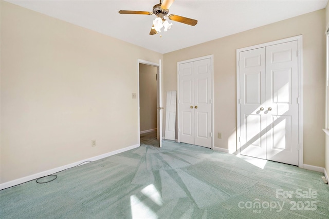 unfurnished bedroom with a ceiling fan, light carpet, baseboards, and two closets