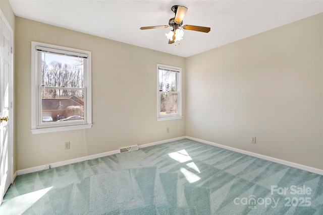 empty room featuring carpet floors, baseboards, visible vents, and ceiling fan