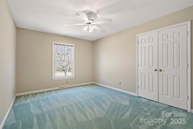 unfurnished bedroom featuring a textured ceiling, visible vents, baseboards, a closet, and carpet