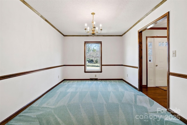 carpeted spare room with a notable chandelier, crown molding, and baseboards