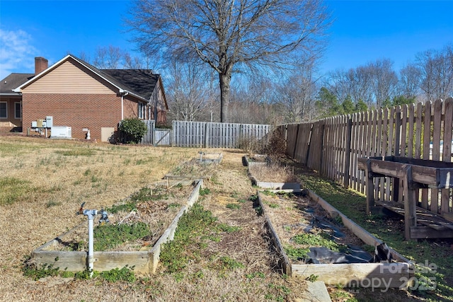 view of yard with a gate, a fenced backyard, and a vegetable garden