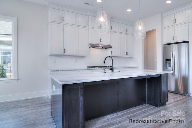 kitchen featuring under cabinet range hood, visible vents, white cabinets, stainless steel refrigerator with ice dispenser, and backsplash