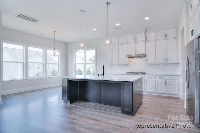 kitchen with visible vents, white cabinets, freestanding refrigerator, gas stovetop, and backsplash