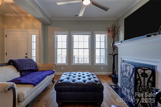 living room featuring a healthy amount of sunlight, baseboards, ornamental molding, and wood finished floors