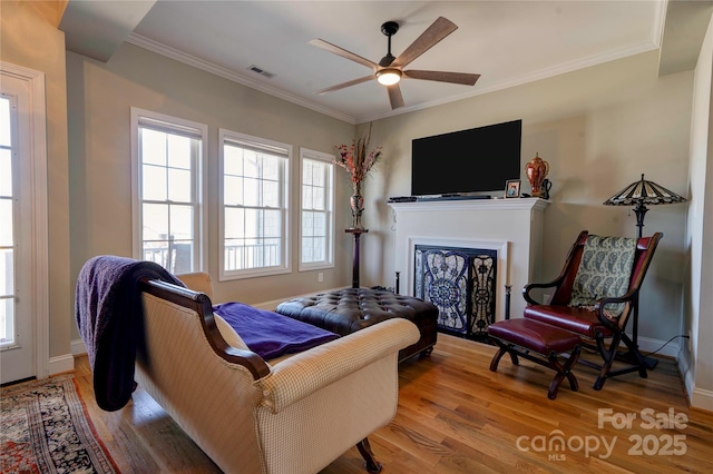 living area with light wood-style flooring, baseboards, and crown molding