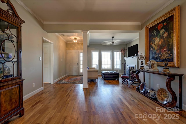 entrance foyer with ornamental molding, a fireplace, decorative columns, and wood finished floors