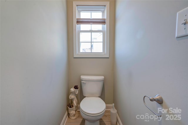 half bathroom featuring toilet and baseboards