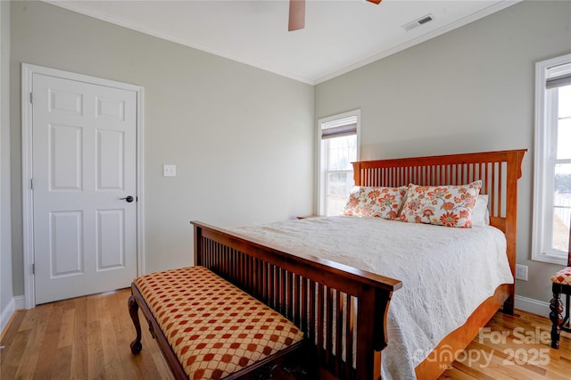 bedroom featuring baseboards, visible vents, ceiling fan, wood finished floors, and crown molding