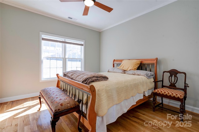 bedroom with crown molding, visible vents, ceiling fan, wood finished floors, and baseboards