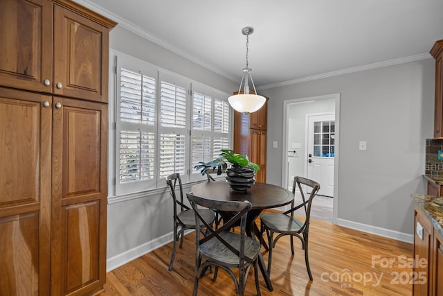 dining space featuring crown molding, light wood-style flooring, and baseboards