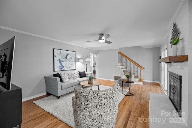 living area with baseboards, light wood-style flooring, stairway, crown molding, and a fireplace