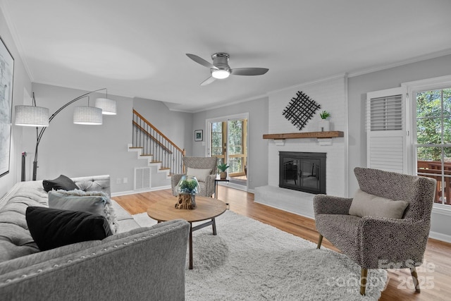 living room with light wood-style floors, stairs, visible vents, and crown molding