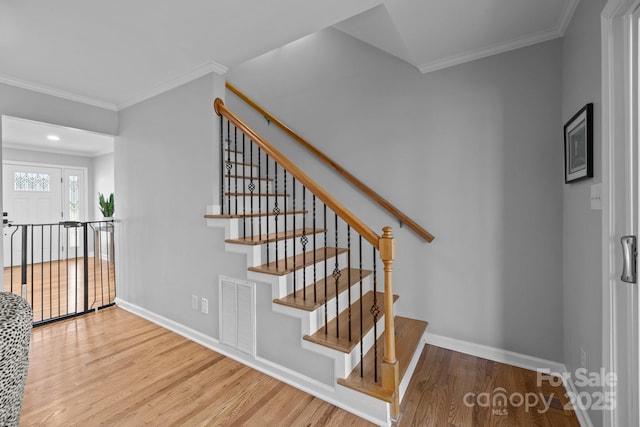 stairs with visible vents, crown molding, baseboards, and wood finished floors