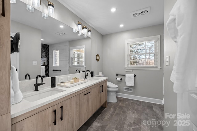 full bathroom with toilet, baseboards, visible vents, and a sink