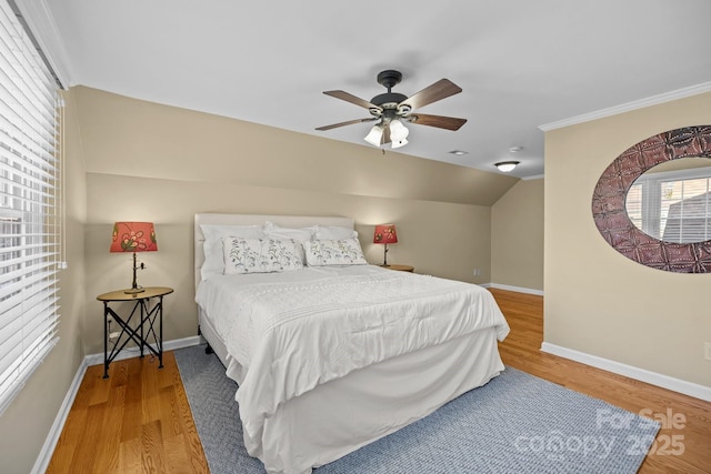 bedroom featuring lofted ceiling, a ceiling fan, ornamental molding, wood finished floors, and baseboards