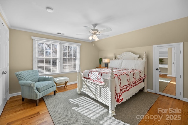 bedroom featuring wood finished floors, a ceiling fan, visible vents, vaulted ceiling, and baseboards