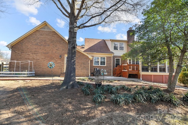 back of property with a chimney, a deck, a patio, and brick siding