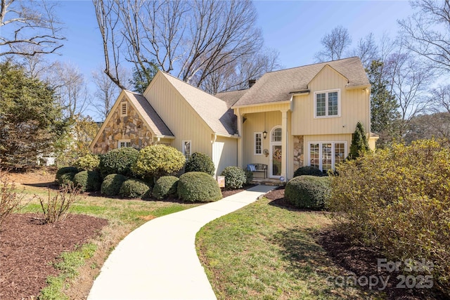 view of front of house featuring stone siding, roof with shingles, and a front lawn