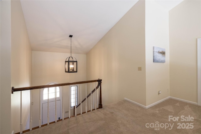 staircase with baseboards, high vaulted ceiling, carpet flooring, and an inviting chandelier