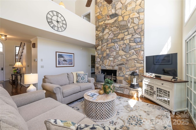 living area with a fireplace, wood finished floors, and a towering ceiling