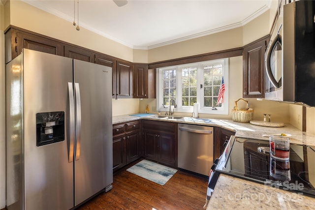 kitchen featuring dark wood finished floors, stainless steel appliances, ornamental molding, dark brown cabinetry, and a sink